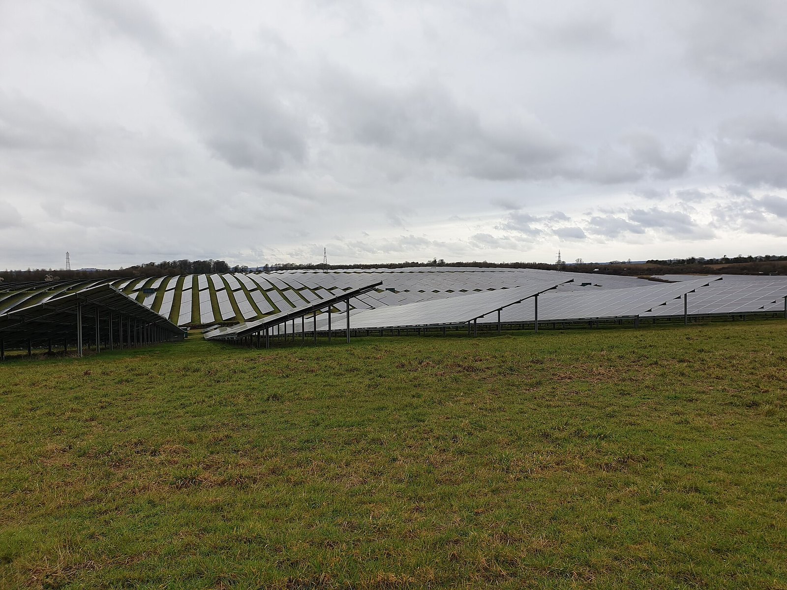 Grande surface plane enherbée au pied d'un parc de panneaux solaires photovoltaïques